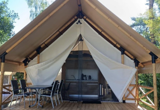 Tienda glamping en Reestervallei, Países Bajos, con terraza de madera, mesa y sillas al aire libre.