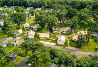 Aerial view of glamping tents and lodges at Reestervallei in the Netherlands, nestled within green woods.