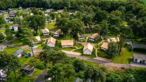 Vue aérienne de tentes glamping et lodges à Reestervallei aux Pays-Bas, entourés de verdure et d’arbres.