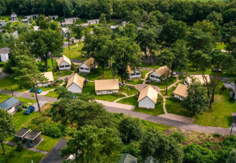 Vista aérea de tiendas glamping y cabañas en Reestervallei, Países Bajos, rodeadas de vegetación y árboles.