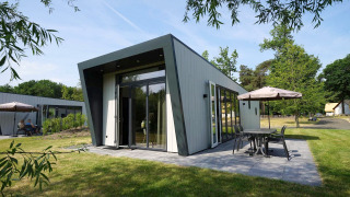 Lodge Just Nature moderne avec grande terrasse et coin repas extérieur dans un cadre verdoyant.