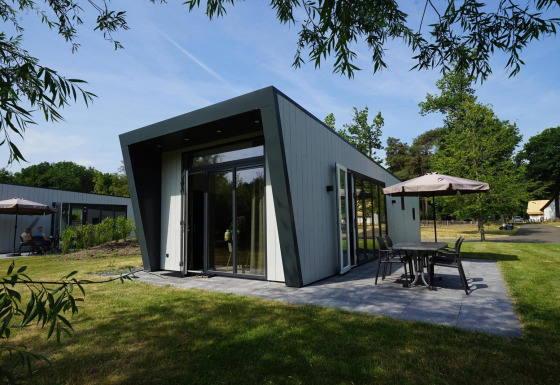 Lodge Just Nature moderne avec grande terrasse et coin repas extérieur dans un cadre verdoyant.
