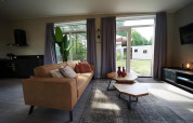 Modernes Wohnzimmer in der Just Nature Lodge, Reestervallei, Niederlande, mit großen Fenstern.