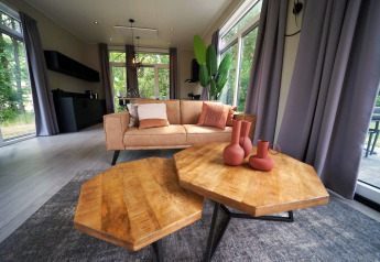 Modernes Wohnzimmer in der Just Nature Lodge, Reestervallei Niederlande, mit Holztisch und Couch.
