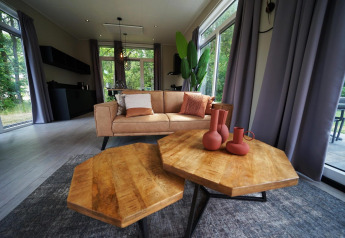 Salón moderno en Just Nature en Reestervallei, Países Bajos, con mesas de madera y sofá acogedor.