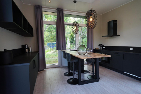 Moderne køkken og spiseområde med store vinduer i Just Nature lodge, Reestervallei, Holland.