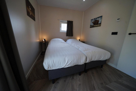 Moderno dormitorio en la cabaña Just Nature en Reestervallei, Países Bajos, con dos camas individuales y decoración sencilla.