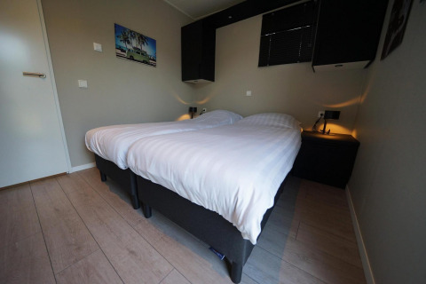 Dormitorio moderno en Just Nature lodge en Reestervallei, Países Bajos, con dos camas individuales y decoración.