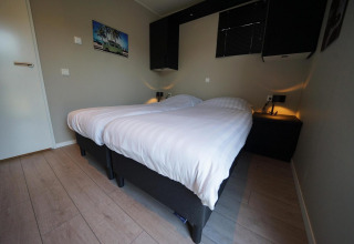 Chambre moderne à la lodge Just Nature à Reestervallei, Pays-Bas, avec deux lits simples et décoration.