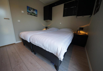 Dormitorio moderno en Just Nature lodge en Reestervallei, Países Bajos, con dos camas individuales y decoración.