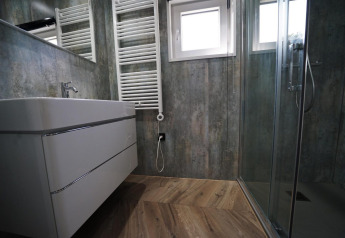 Modernes Badezimmer mit Glasdusche, Holzoptikboden, Wandwaschbecken und Handtuchheizkörper, Reestervallei.