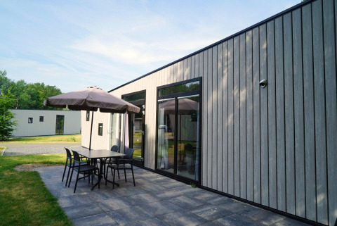 Lodge moderne Just Nature Light à Reestervallei, Pays-Bas, avec terrasse, table, chaises et parasol.