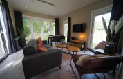 Moderne lodge Just Nature Light i Reestervallei, Holland, med store vinduer og hyggelig indretning.