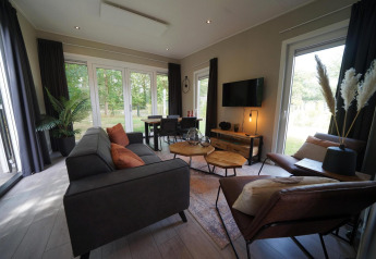 Moderne Just Nature Light lodge in Reestervallei, Nederland, ruime zithoek en grote ramen met uitzicht op natuur.