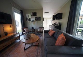 Moderne leefruimte in Just Nature Light-lodge te Reestervallei, Nederland, met grote ramen en knusse sfeer.