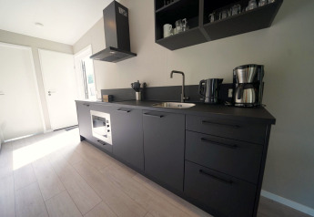 Moderne schwarze Küche in der Just Nature Light Lodge in Reestervallei, Niederlande, mit stilvollem Design.