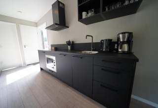 Modern black kitchen at Just Nature Light lodge in Reestervallei, Netherlands, with minimalist decor.