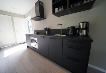 Moderne sort køkken ved Just Nature Light lodge på Reestervallei, Holland, med minimalistisk design.