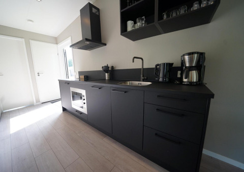 Moderne sort køkken ved Just Nature Light lodge på Reestervallei, Holland, med minimalistisk design.