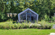 Et billede af det lille hus Solo Retreat på Reestervallei, Holland, omgivet af grønt og skov.