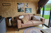 Soggiorno moderno in tiny house Solo Retreat a Reestervallei, Paesi Bassi, con divano e vista lago.