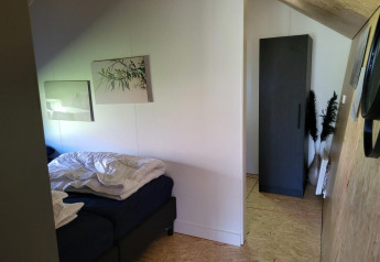 Schlafzimmer im Tiny House Solo Retreat in Reestervallei, Niederlande, mit Bett und Schrank.