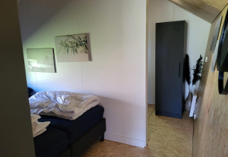 Slaapkamer in het tiny house Solo Retreat bij Reestervallei, Nederland, met bed en kast.