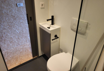 Kleines Badezimmer im Solo Retreat, Reestervallei, Niederlande mit Toilette, kleinem Waschbecken und moderner Ausstattung.