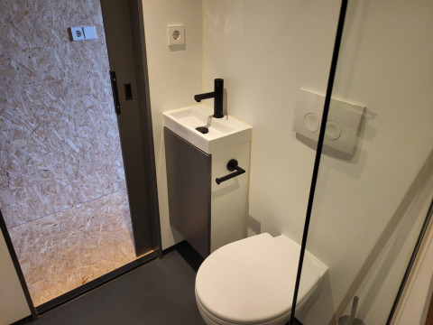 Lille badeværelse i Solo Retreat, Reestervallei, Holland, med toilet, lille håndvask og moderne indretning.