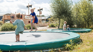 Niños juegan en camas elásticas integradas en el parque vacacional FarmCamps BoeBaDoe en Limburgo, Países Bajos.