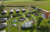 Luchtfoto van FarmCamps De Bonte Fries vakantiehoeve in Friesland, Nederland, met tenten en speelplein.