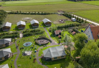 Luchtfoto van FarmCamps De Bonte Fries vakantiehoeve in Friesland, Nederland, met tenten en speelplein.