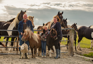 Familieposerer med ponyer, får og heste på FarmCamps De Bonte Fries i Friesland, Holland, under skyet himmel.
