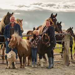Familia posando con ponis, oveja y caballos en FarmCamps De Bonte Fries, Friesland, Países Bajos, al aire libre.