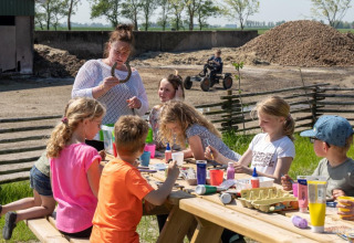Kinder basteln im Freien mit einem Erwachsenen auf FarmCamps De Bonte Fries, Ferienpark in Friesland, Niederlande.