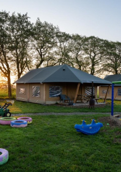 Área de juegos con arenero, juguetes y tiendas de campaña al atardecer en FarmCamps De Bonte Fries, Frisia, Países Bajos.