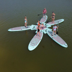 Personas de pie en tablas de paddle interconectadas en forma de flor, sobre un lago en FarmCamps De Bosrand.