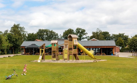 Speeltuin met glijbanen op FarmCamps De Bosrand vakantiepark in Drenthe, Nederland, met spelende kinderen.