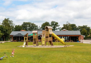 Spielplatz mit Rutschen bei FarmCamps De Bosrand, einem Ferienpark in Drenthe, Niederlande, mit spielenden Kindern.