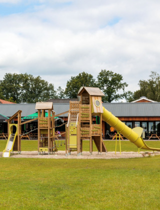 Parque infantil con toboganes en FarmCamps De Bosrand, parque vacacional en Drenthe, Países Bajos, con niños jugando.