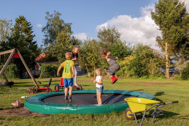 Kinder spielen und springen auf einem Trampolin auf dem Gelände von FarmCamps De Bosrand, Drenthe.