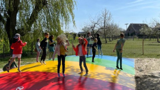 Kinder springen fröhlich auf einem bunten Luftkissen bei FarmCamps De Buitenhoeve in Gelderland, Niederlande.