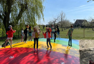 Bambini giocano e saltano su un grande cuscino colorato a FarmCamps De Buitenhoeve, Gelderland, Paesi Bassi.