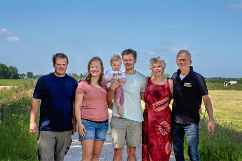Eine Familie steht auf einem Feldweg auf FarmCamps De Geele Bosch, Friesland, Niederlande, an einem sonnigen Tag.