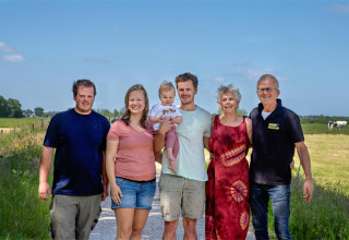 Eine Familie steht auf einem Feldweg auf FarmCamps De Geele Bosch, Friesland, Niederlande, an einem sonnigen Tag.