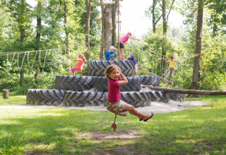 Bambini che giocano su un parco giochi con grandi pneumatici a FarmCamps De Geele Bosch, Friesland, Paesi Bassi.