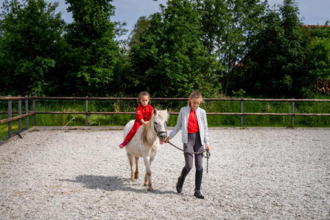 Two children enjoy a horse riding lesson at FarmCamps De Geele Bosch holiday park in Friesland, Netherlands.