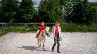 Dos niños disfrutan de una clase de equitación en FarmCamps De Geele Bosch, Friesland, Países Bajos.