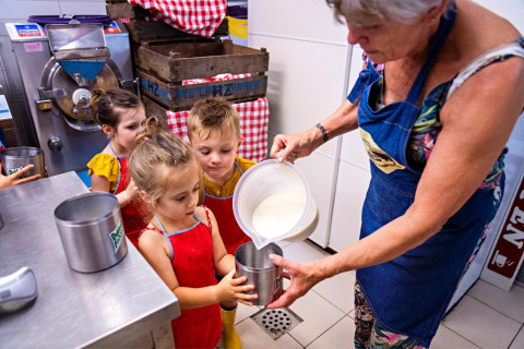 Kinder helfen einem Erwachsenen bei der Eisherstellung auf FarmCamps De Geele Bosch in Friesland, Niederlande.