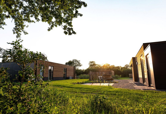 Buitenbeeld van Vacation villa Amalia 4 met hottub bij Hofparken De Bergvennen in Nederland bij zonsondergang.
